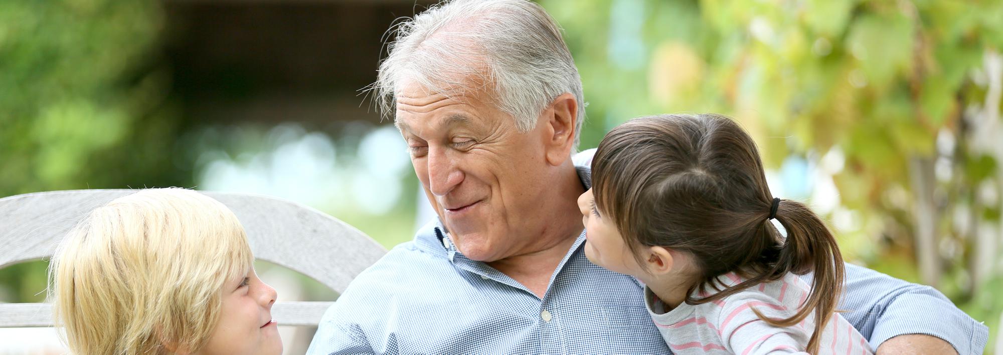 A grandfather sharing a moment with two grandchildren outdoors